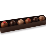 Row of six assorted chocolate truffles in a long dark brown box