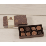 Open box of assorted chocolates beside its lid on a light wood surface