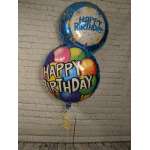 Two birthday balloons against a brick wall, one multicolor and one blue
