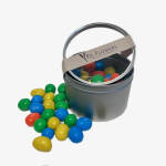 Bucket of colorful candy-coated chocolates with some spilled out
