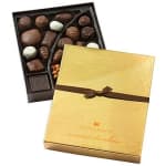 Box of assorted chocolates with a gold lid and ribbon