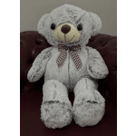 Gray teddy bear with a plaid bow sitting on a dark chair