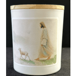 White candle in a jar with a peach-toned label showing a woman and lamb