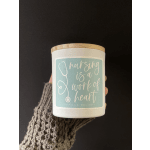 White candle jar with a wooden lid and teal label