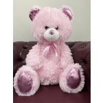 Pink teddy bear with a satin ribbon sitting on a couch