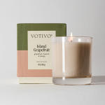 Lit glass candle in front of a Votivo box