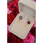 Earrings in a beige jewelry box surrounded by red and pink roses