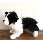 Black and white plush dog figurine standing on a wooden surface