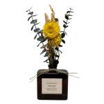 Yellow dried flower arrangement in a dark glass diffuser bottle