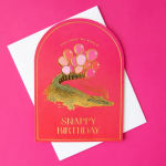 Pink birthday card with a gold crocodile and balloons