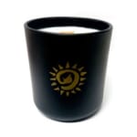 Black candle in a matte holder with a gold sun emblem