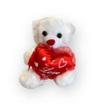 White teddy bear holding a red heart pillow
