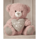 Pink plush teddy bear holding a heart pillow