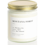 A jar candle with a gold lid and white label reading Montana Forest.