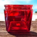Red glass jar candle on a wooden surface