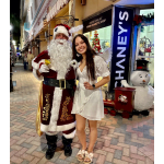 Santa posing with a woman in a white dress on a decorated sidewalk