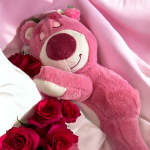 Pink teddy bear with red roses nestled around it