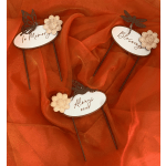 Three memorial garden stakes with butterfly and flower accents on orange fabric