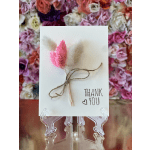 Thank-you card with pink dried flowers tied with twine on a clear stand