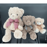 Three teddy bears with ribbon bows sit together on a dark surface.