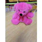 Pink teddy bear with a ribbon bow sitting on a wooden surface