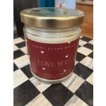 A scented candle in a glass jar with a gold lid and "Love You" label