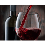 Red wine being poured into a glass with a wine bottle behind it