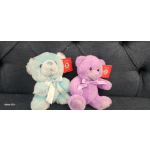 Two plush teddy bears with ribbons, one blue and one purple.