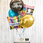 Cluster of birthday balloons with colorful printed designs and a gold balloon
