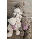 Four plush teddy bears with ribbon bows arranged on a wooden floor