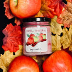 Apple cinnamon candle in a glass jar surrounded by autumn leaves and apples