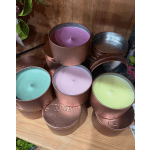 Assorted pastel candles in round metal tins stacked on a wooden surface