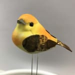 Small yellow bird figurine on thin metal legs