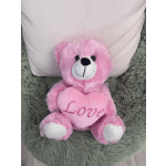 Pink teddy bear holding a heart that says Love