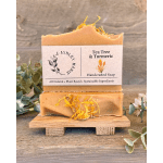 Two bars of tea tree and turmeric soap on a small wooden stand