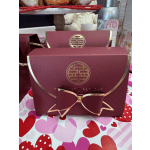 Maroon gift boxes with gold trim and bow accents on a heart-patterned surface