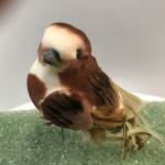 Small brown-and-white bird figurine on green textured base