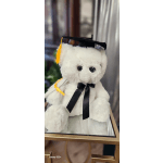 White teddy bear wearing a graduation cap and black ribbon