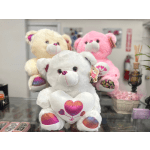 Three plush teddy bears with heart designs on a store counter