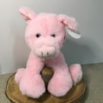 Pink plush pig toy sitting on a wood slice base