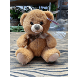 Brown teddy bear with a ribbon bow sitting on a wooden surface