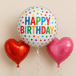 Three birthday balloons, including a polka-dot Happy Birthday balloon and two heart balloons