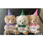 Three teddy bears wearing birthday hats and "Happy Birthday" bibs