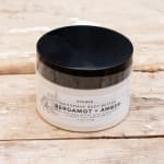 Jar of bergamot and amber body butter with a black lid