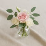 Pink and white roses in a small clear glass vase