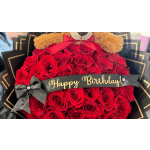 Bouquet of red roses with a teddy bear and birthday ribbon