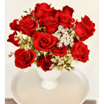 Red roses arranged in a white vase with small white filler flowers