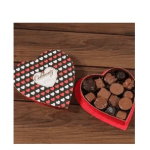Heart-shaped chocolate box with assorted chocolates on a wooden surface