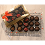 Box of assorted chocolates with a red ribbon on a clear tray