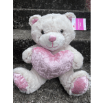 White teddy bear holding a pink heart pillow